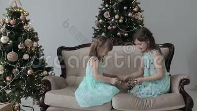 两个女孩坐在房子的地板上，拿着圣诞礼物和一个花环。 女孩玩花环